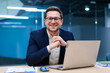 © Home-stock - Charismatic European businessman sitting at desk in stylish office working on laptop and ready for business, smiling at camera