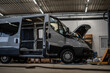 © dexdexfu - Commercial vans in industrial workshop during conversion and assembly. Vehicle interiors exposed, doors open, showing custom transport production, maintenance, and manufacturing process.