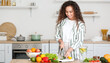© Pixel-Shot - Young African-American woman cutting vegetables in kitchen