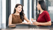 © NAMPIX - Portrait of a cheerful Asian businesswoman smiling and enjoying a coffee break with her colleague in a corporate workspace.