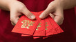 © RG Media - Close-up of hands holding red envelopes symbolizing luck, prosperity, and Chinese New Year traditions.