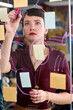 © TrueFrame Collective - Caucasian young adult woman writing on transparent board with marker, surrounded by sticky notes, focusing on brainstorming or planning process in modern office environment
