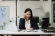 © NINENII - Business woman asian talking phones update plan working on laptop computers, online business.