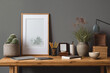 © Tohamina - A minimalist desk setup with a cactus a framed picture books and a coffee cup