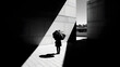 © Muneeb - Solitary figure holding an umbrella stands precisely within a sharply defined geometric beam of sunlight contrasting starkly against dark architectural shadows creating dramatic visual tension