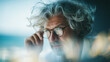 © Вікторія Пащина - A gentleman with silver curls takes a moment to adjust his reading glasses as he engages in a remote meeting from the comfort of his home office, concentrating intently on the material displayed on hi
