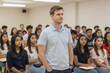 © maria_lh - Young male student standing in a classroom with classmates in the background. Man giving a presentation or speech at university. Education concept