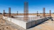 © Vasiliy - Construction site featuring a concrete foundation with vertical steel rebar columns. New residential building project in a suburban development under a blue sky. Copy space