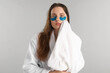 © New Africa - Beautiful woman with eye patches and clean towel on light grey background