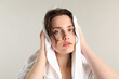 © New Africa - Beautiful woman drying hair with towel on light grey background