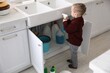 © New Africa - Child safety at home. Little boy playing with cleaning products in kitchen
