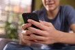 © New Africa - Teenage boy using smartphone on sofa at home, closeup