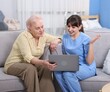 © New Africa - Care worker teaching senior woman to use laptop at retirement home