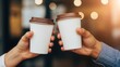 © Eve - Close up of two hands clinking paper coffee cups in cafe interior with warm bokeh light. Friendship, meeting, business break, and coffee shop culture concept. High quality lifestyle image.