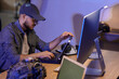 © Pixel-Shot - Young soldier working with military laptop on table in office at night