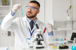© Pixel-Shot - Male scientist with test tubes and microscope at table in laboratory