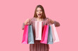 © Pixel-Shot - Surprised young woman with shopping bags on pink background
