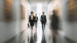 © KeJayStudio - Businesswoman walking in office corridor with colleagues, blurred motion effect creates dynamic and energetic atmosphere in modern workplace environment