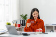 © Kritdanai - Online Shopping and Gift: A young woman is immersed in the excitement of online shopping. Holding a credit card and gift box, she reflects on the joy of gifting and purchases.