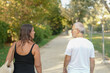 © Masakazu Tokashiki - A man and a woman are walking together on a path. The man is wearing a white shirt and the woman is wearing a black tank top. They are both carrying handbags. Scene is casual and relaxed