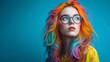 © florynstudio3 - Portrait of a young woman with vibrant, multicolored hair, wearing round glasses, against a solid blue background