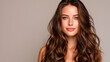 © Enrique - Beautiful woman with long, wavy hair posing against a neutral background showcasing natural beauty and elegance with soft makeup and glowing skin