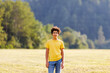 © Ktn - Teen male standing in sunny field with forest background
