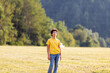 © Ktn - Young hispanic male in yellow shirt standing in field against forested background