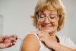 © dsheremeta - Senior woman smiling receiving vaccination in shoulder