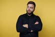 © bodnarphoto - Man in black shirt with arms crossed against yellow background.