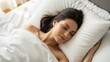© Eve - Beautiful young woman with brunette hair sleeping peacefully in comfortable white bedding. Serene morning rest and healthy sleep concept with natural lighting in bright cozy bedroom area.