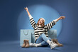 © Pixel-Shot - Stylish young woman with winter boots and shopping bags sitting on blue background
