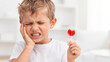 © Taras Roshchuk - Boy shows discomfort from tooth pain while holding a lollipop after eating it