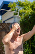 © travelview - man has a shower in the garden