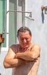 © travelview - man has a shower in the garden