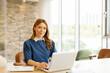 © Westend61 - Businesswoman working on a laptop at a desk in a modern office with natural light