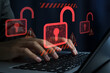 © tadamichi - Hacking and system intrusion. Unauthorized access and account takeover. Unlocked padlock icons. Hacker using laptop computer to steal data.