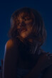 © kinomaster - A captivating portrait of a young female model, illuminated by dramatic blue muted lighting that creates a mysterious and alluring atmosphere.