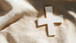 © A2Z AI  - A minimalist tableau featuring a white geometric cross resting on a textured, cream-colored fabric, illuminated by soft, filtered light casting subtle shadows.