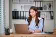 © wattana - Confident businesswoman working on her laptop in a modern office.