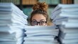 © miss irine - Young woman with glasses peeks over huge piles of paper on desk. Looks surprised by extreme workload, chaotic office environment. Many stacks of documents, files create overwhelming situation. Eyes