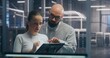© Framestock - Male and Female IT Engineer Team Collaborating and Discussing Data Displayed on Digital Tablet, Standing in Secure, High Tech Environment of Data Center. Concept Teamwork and Mobile System Diagnostic.
