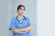 © SOMKID - Portrait of asian female doctor looking at camera with crossed arms in modern clinic, Doctor woman wearing glasses and medical coat working in hospital.