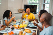 © Nexa - Happy African American family enjoying a healthy breakfast together at a dining table in a bright kitchen, laughing and talking while sharing fresh food and juice.