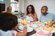 © Nexa - Happy Black family enjoying a healthy breakfast together at the dining table, sharing food and conversation in a bright home kitchen.