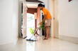 © Nexa - Young man cleaning the tiled floor with a mop in a bright modern home hallway.