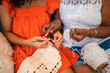 © Nexa - Close-up of an African American grandmother teaching her granddaughter how to crochet at home, focusing on their hands and the white yarn.
