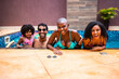 © Nexa - Happy multi-ethnic family and friends smiling while leaning on the edge of a swimming pool during a sunny summer day.