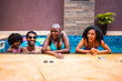 © Nexa - Happy diverse family or friends laughing together at the edge of a swimming pool on a sunny summer day.