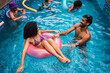 © Nexa - Happy diverse group of friends and family enjoying a summer day in a swimming pool with colorful inflatable rings.